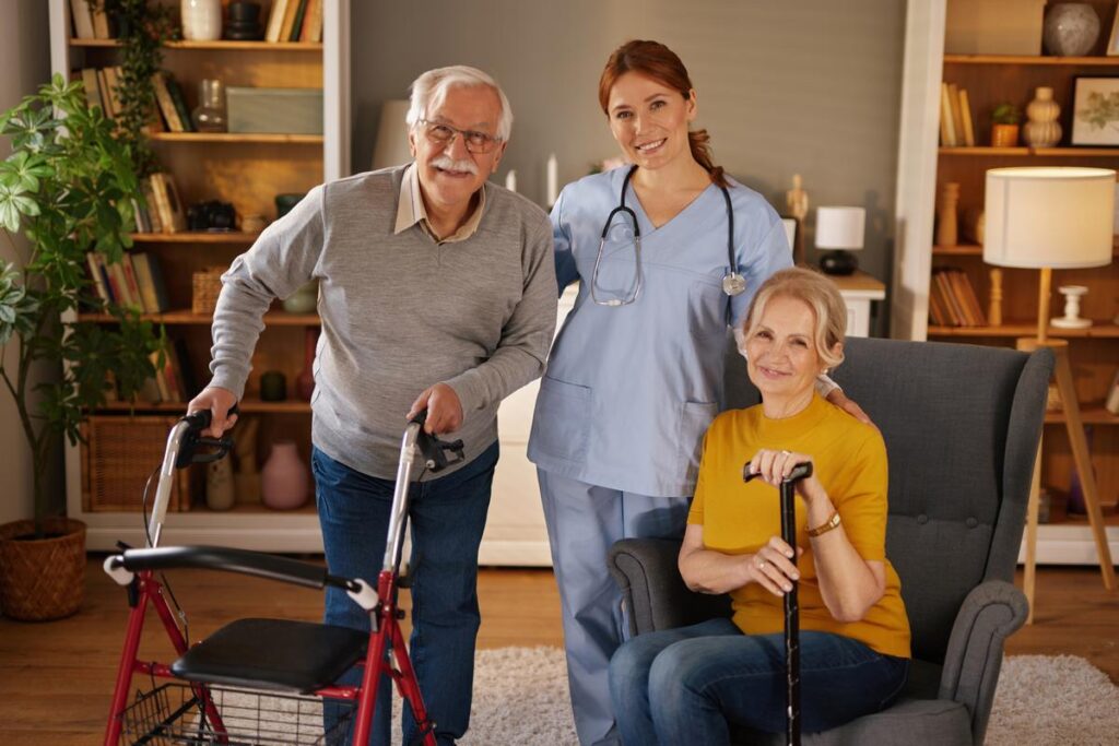 Happy nurse smiling at camera while posing with elderly couple using walking aids, enjoying home care assistance